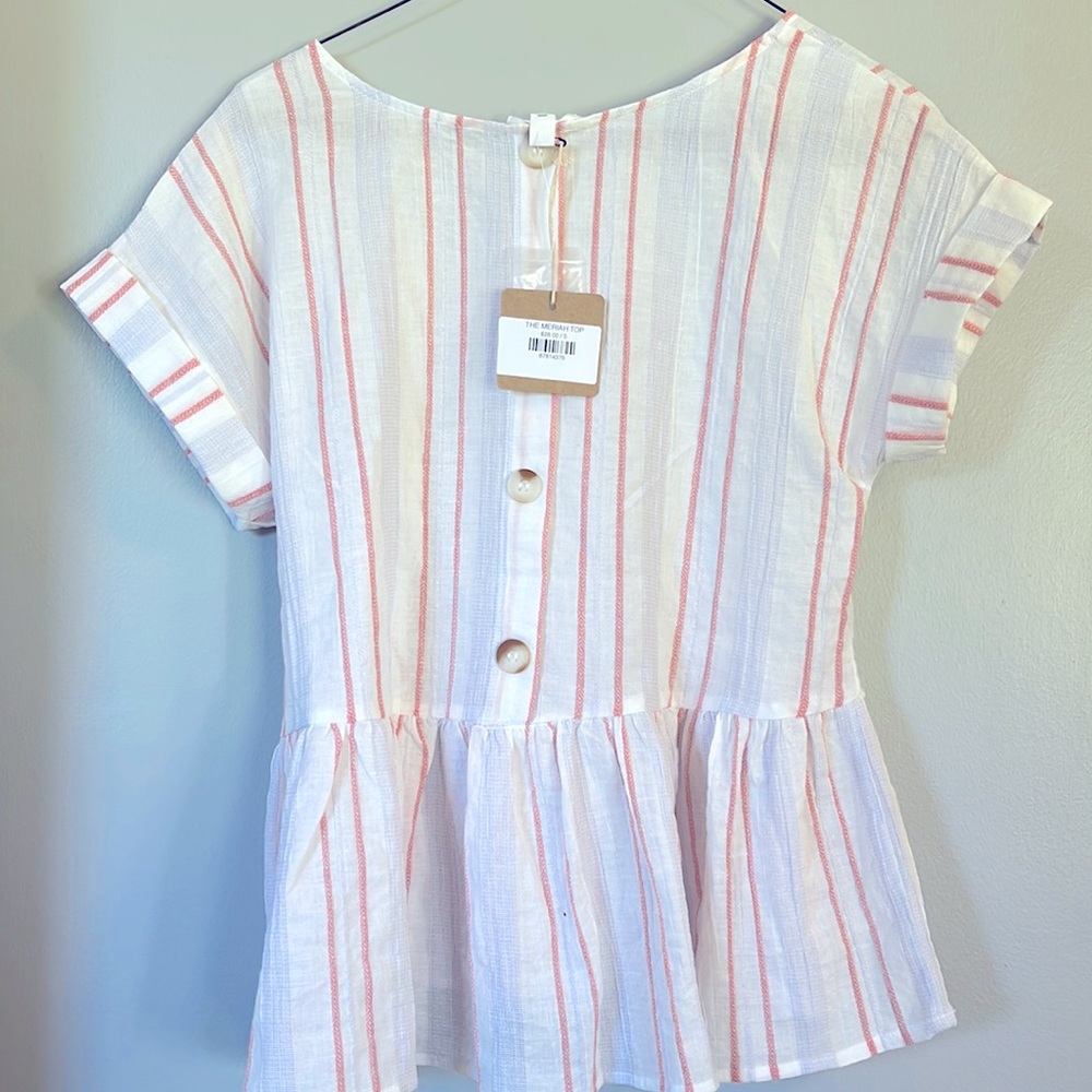 This is a pink and white loose fitting shirt. It has buttons on the front.